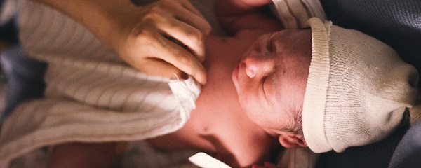 Person covering infant with swaddling blanket